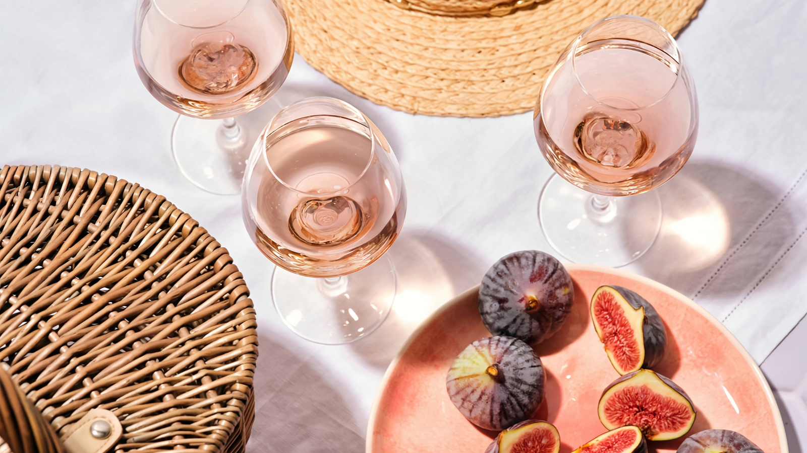 Un pique-nique estival avec du vin rosé, des figues et un chapeau de paille.