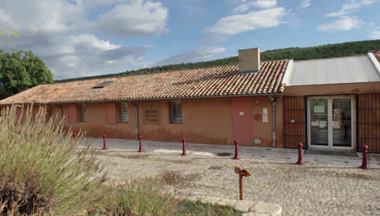 Un bâtiment rustique avec une toiture en tuiles rouges, situé dans un paysage rural.