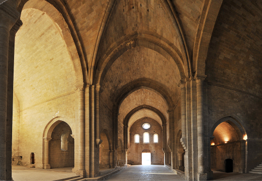 Une église romane avec des voûtes d'arc et des colonnes massives, offrant une vue intérieure lumineuse.