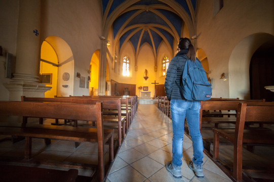 Une personne regarde l'intérieur d'une église gothique avec des travées voûtées.