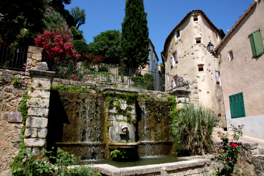 Une fontaine en pierre dans un jardin pittoresque d'un village provençal.