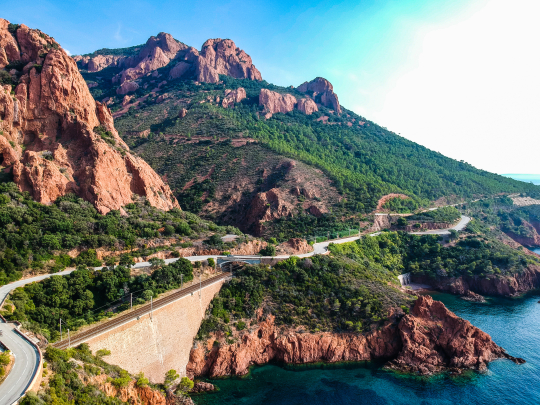 Paysage montagneux corse spectaculaire avec une route sinueuse et la mer.