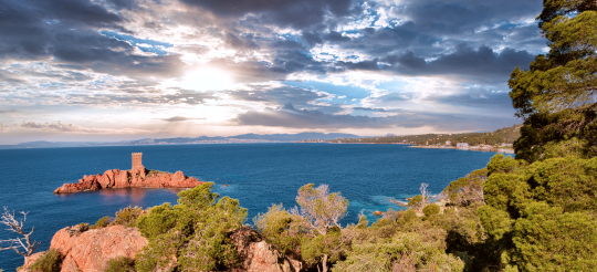 Vue spectaculaire de la tour génoise sur la côte corse, sous un ciel nuageux et lumineux.