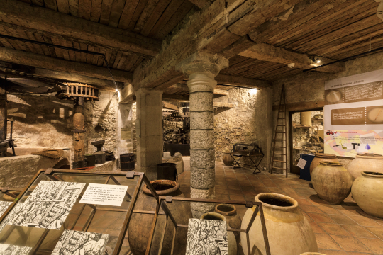 Intérieur de la crypte médiévale, avec des objets et des amphores exposés dans un espace rocheux.