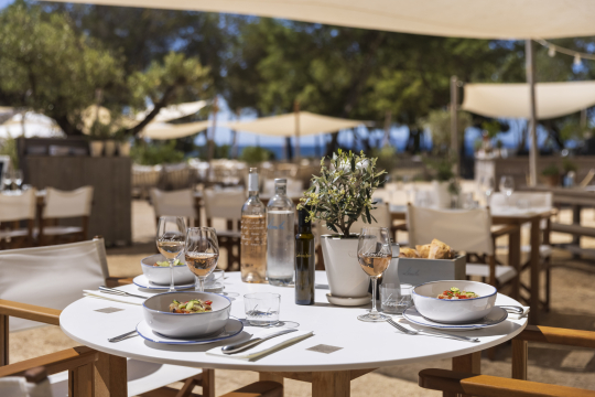 Une table élégante en bord de mer, avec des mets raffinés et du vin.