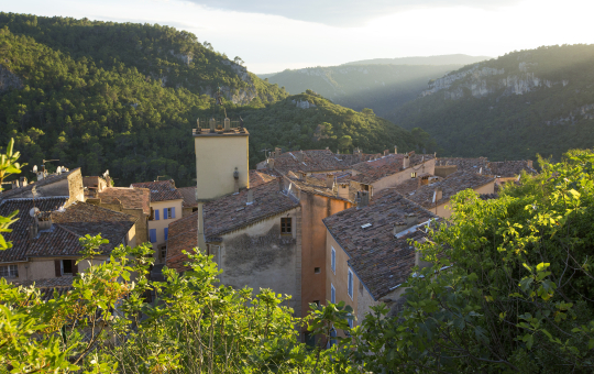 Un village pittoresque niché au creux d'une vallée verdoyante, sous un ciel lumineux.