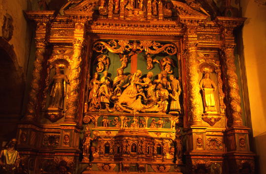 Sculpture dorée d'une scène religieuse, détails complexes et figures sculptées.