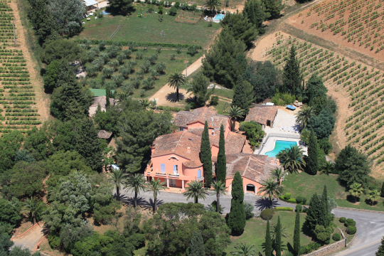 Maison de campagne avec piscine, entourée de vignes et d'oliveraies, vue aérienne.