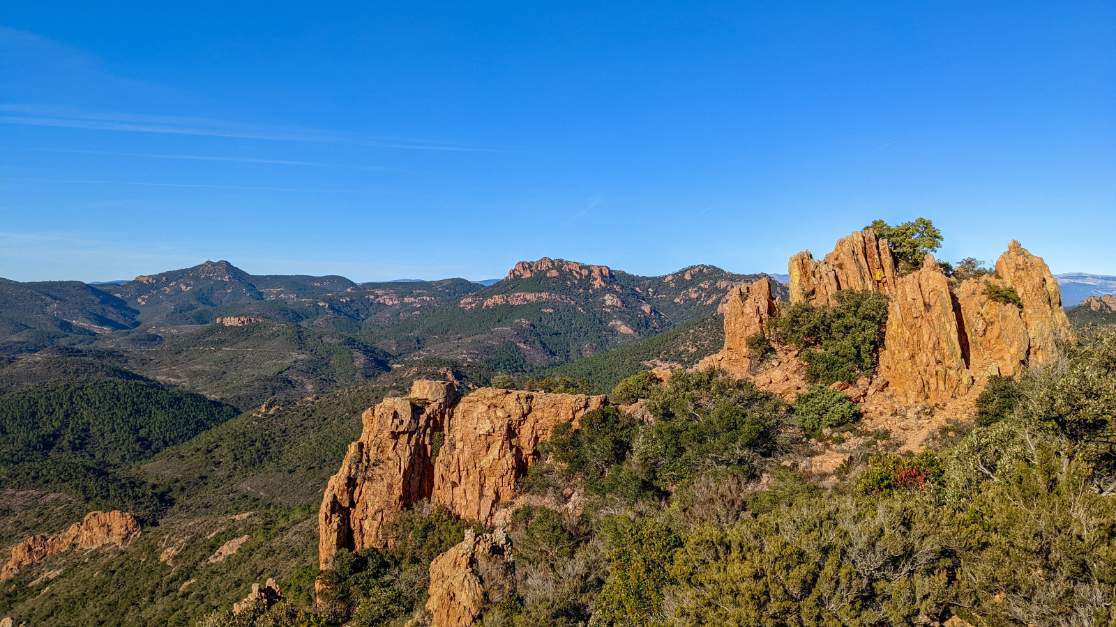 Paysage montagneux et forestier sous un ciel bleu éclatant, vue panoramique.