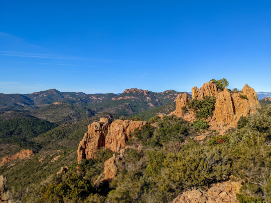 Paysage montagneux et forestier sous un ciel bleu éclatant, vue panoramique.