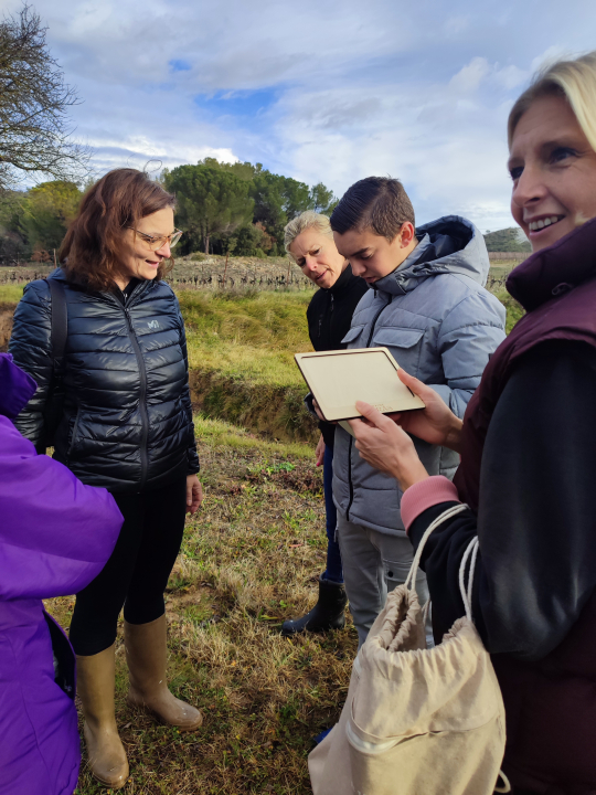 Des personnes examinent un paysage rural avec une tablette, probablement pour une étude environnementale.