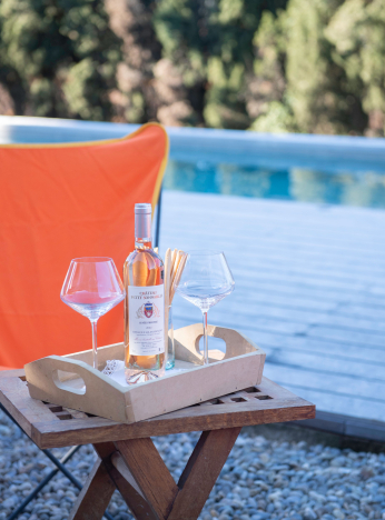 Un plateau avec du vin et des verres près d'une piscine, ambiance détente et rosé.
