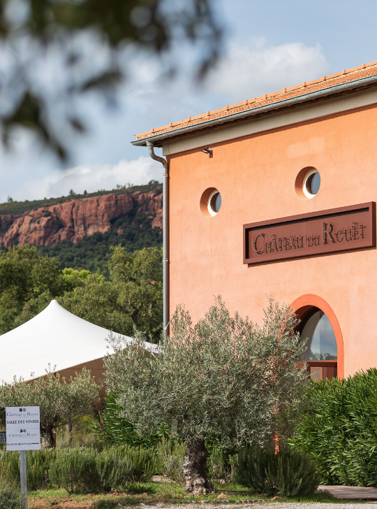 Château du Reulet, élégant bâtiment ocre avec une tente blanche, paysage méditerranéen.