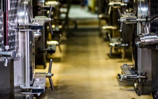 Ligne de fermentation industrielle avec des cuves métalliques, ambiance sombre et mystérieuse.
