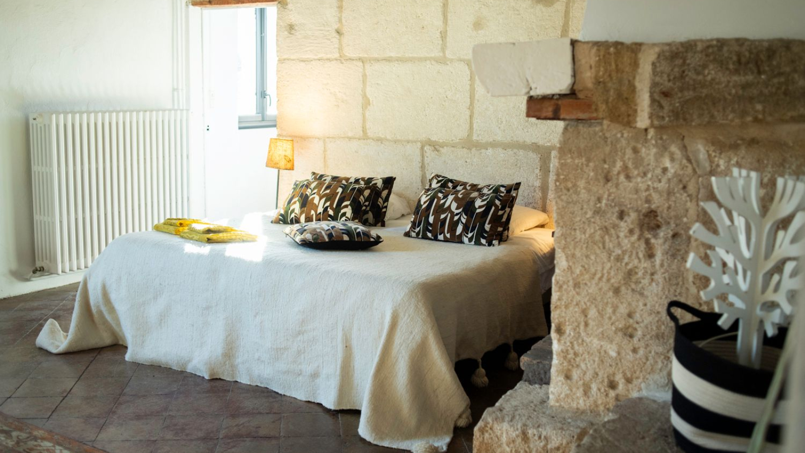 Une chambre rustique et chaleureuse avec un lit drapé et des murs en pierre.