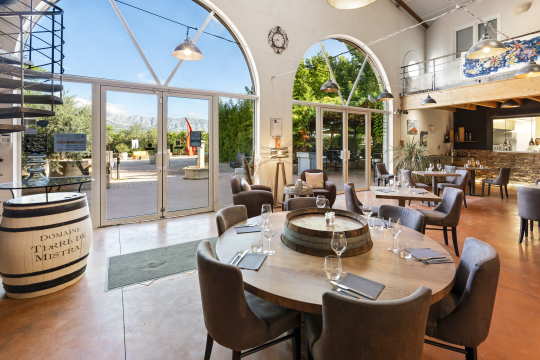Intérieur chaleureux d'un restaurant de domaine viticole avec tables et décor rustique.
