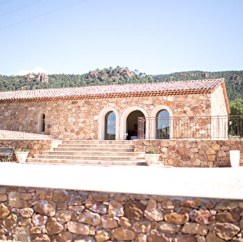 Belle maison en pierre avec toit en tuiles, entourée de verdure et de montagnes.