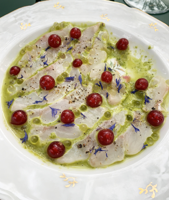 Un délicieux carpaccio de poisson blanc sur lit de pistaches et fleurs comestibles.