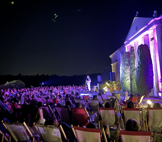 Spectacle de musique en plein air avec un public nombreux sous la nuit étoilée.