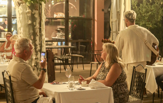 Un couple dîne en terrasse illuminée, dans un restaurant pittoresque au soir.