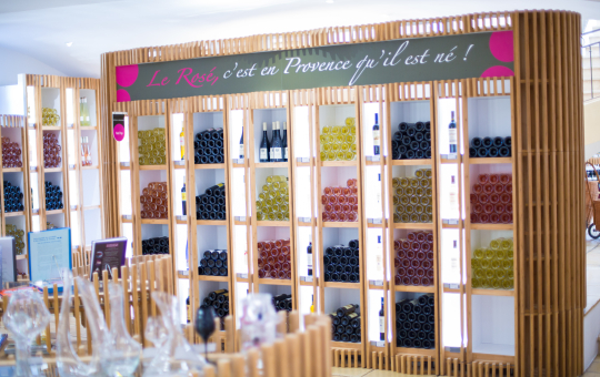 Présentation d'une étagère remplie de bouteilles de rosé provençal dans une boutique.