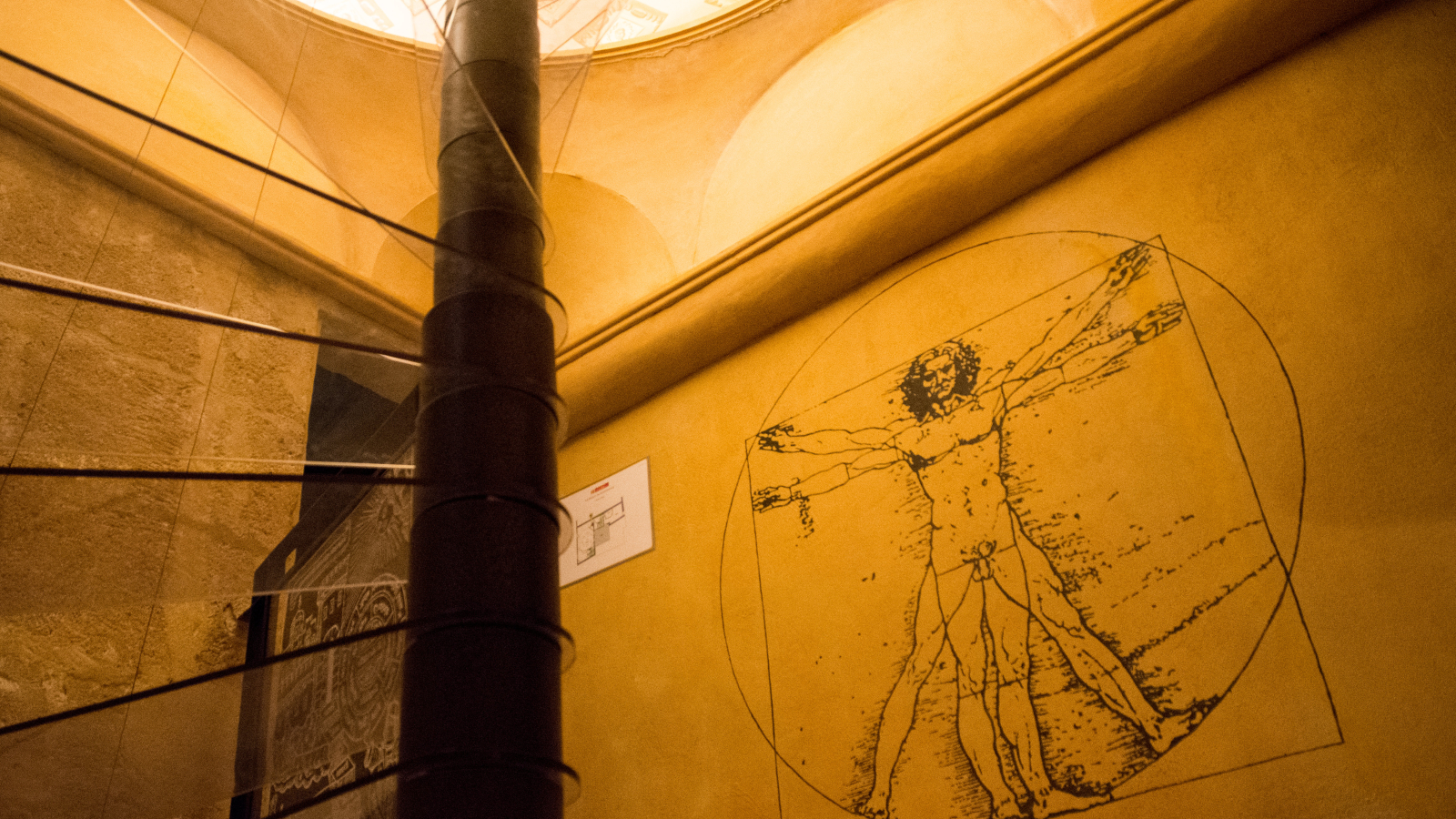 Dessin de la Vitruvian Man sur un mur jaune dans un couloir de château.