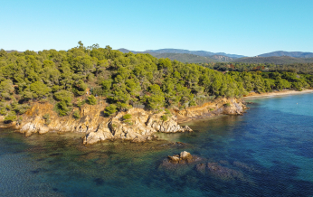 Vue aérienne d'une côte rocheuse et verdoyante avec une mer bleue et limpide.