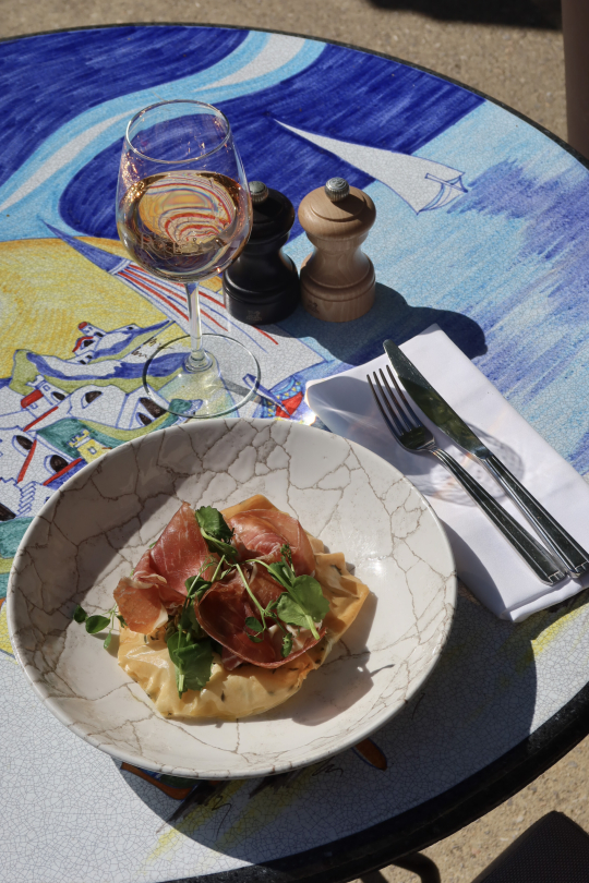 Un délicieux plat de pâtes au jambon cru et roquette, accompagné d'un verre de vin.