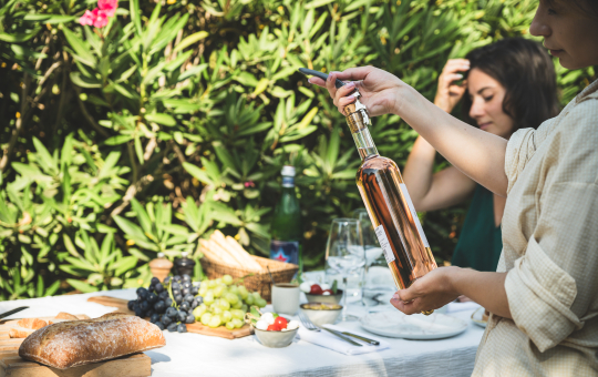 Une femme sert du vin rosé lors d'un pique-nique en plein air avec une amie.