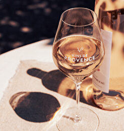 Un verre de vin rosé Vins de Provence, illuminé par le soleil, sur une nappe noire.