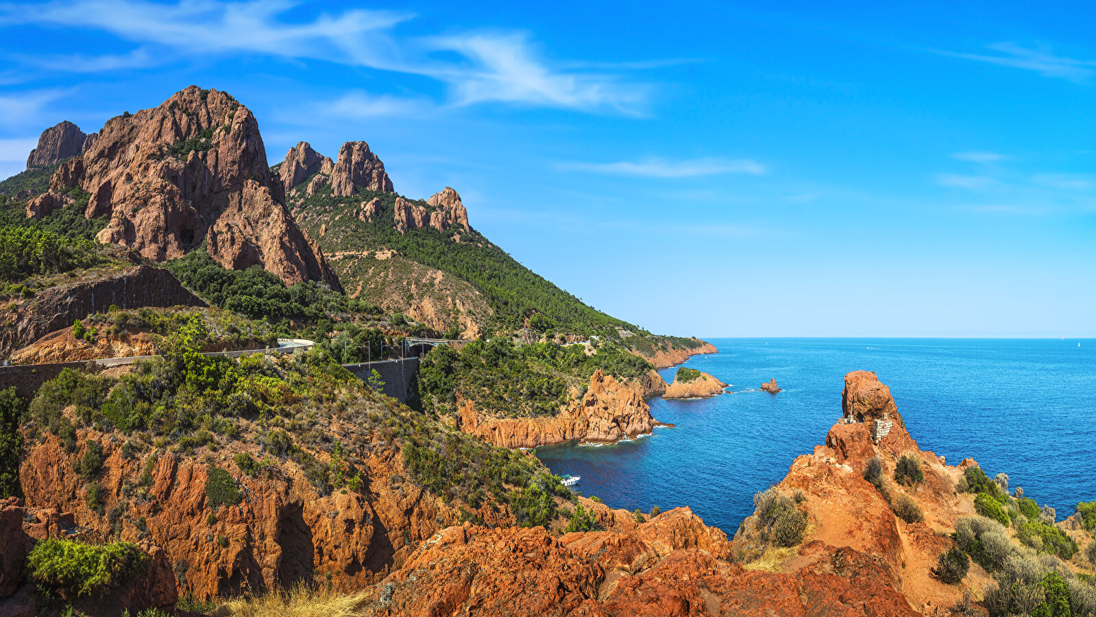 Paysage côtier spectaculaire de la Corse avec des montagnes, la mer et un ciel bleu.