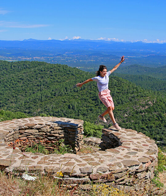 Une femme joyeuse profite d'une vue imprenable sur les montagnes et la vallée.