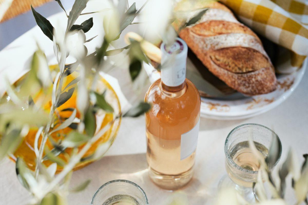Bouteille de rosé de Provence, verres et pain sur une table à l’ombre d’un olivier